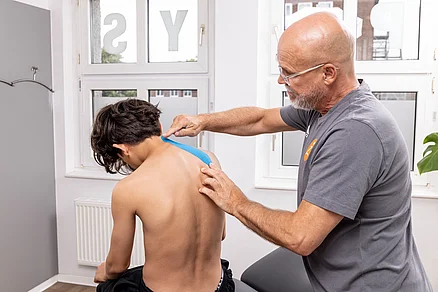 Hier ist ein Patient mit anhaltenden Kopfschmerzen. Diese können aufgrund verspannte Muskulatur entstehen. Das Tape wird oben an der kurzen Nackenmuskulatur bis zum Schulterblatt angelegt. Diese Anlage ist besonders effektiv bei Kopfschmerzpatienten . Kopfschmerzen Behandlung