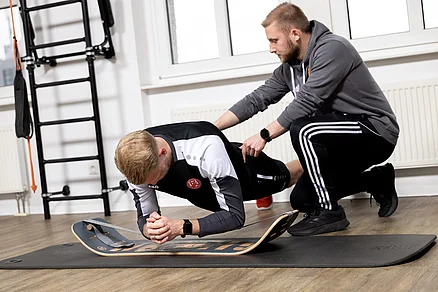 Plank Unterarmstütz auf dem Giboard. Die Bauchmuskeln Musculus rectus abdominis und die Rückenmuskeln Musculus trapezius, Musculus latissimus dorsi, Musculus levator scapulae, Musculus rhomboideus und Musculus serratus posterior wer Plank Unterarmstütz