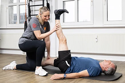 Hier wird mit Hilfe der Trainerin die Rückseite des Oberschenkels (ischiocrurale Muskulatur) gedehnt. Ebenso ist die Wade (Musculus gastrocnemius) in der Dehnung. Personell Training